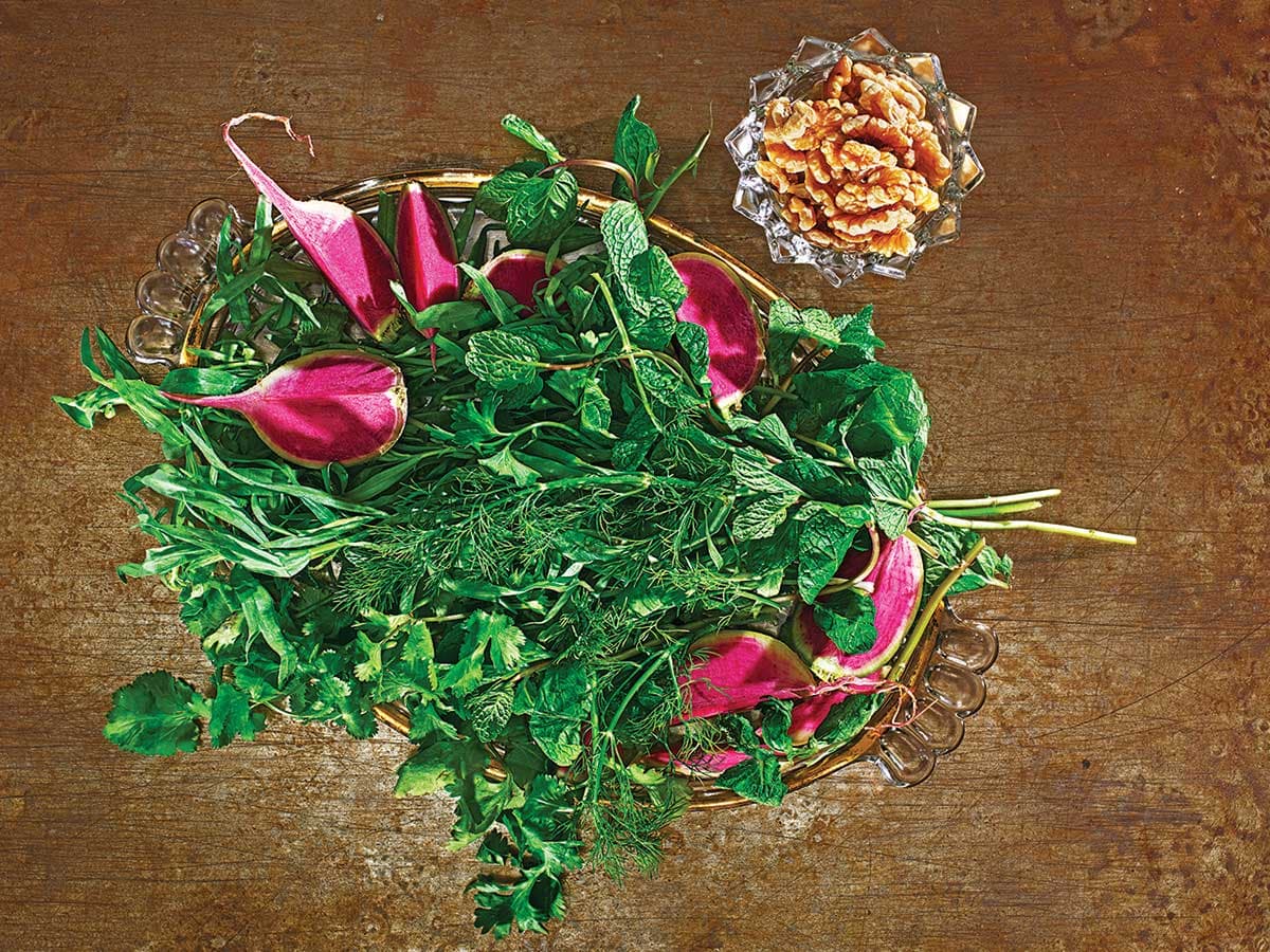 a platter of fresh herbs, alliums, and radishes