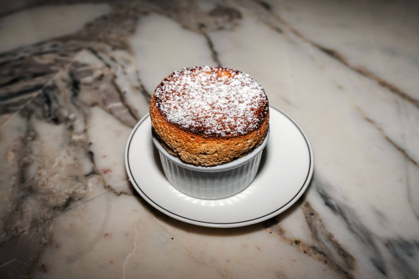 A towering bourbon-pecan soufflé on a white marble table.