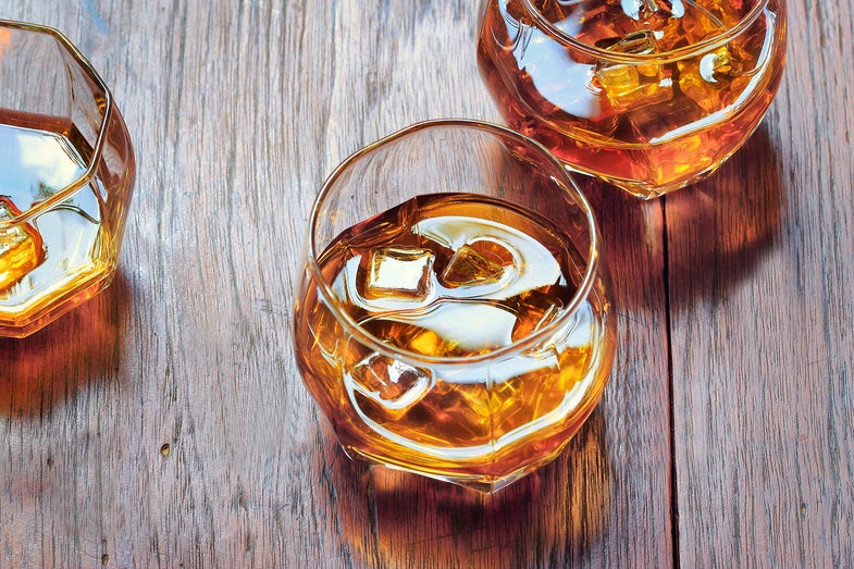 Glass with Whiskey on table rustic wooden background, top view