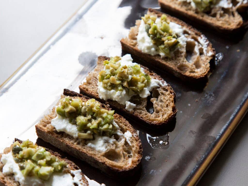 Homemade bread topped with goat cheese and green olives