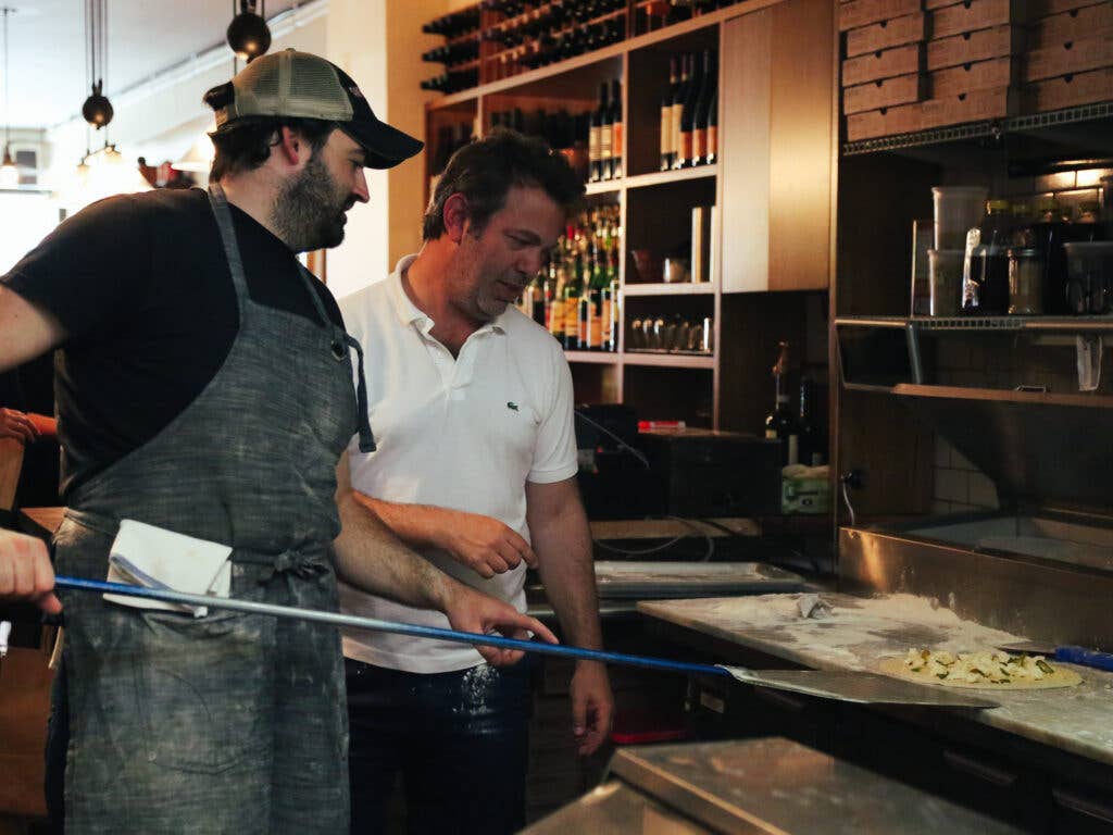 Editor in Chief Adam Sachs watches pizza bake with Matt Hyland of Emily.