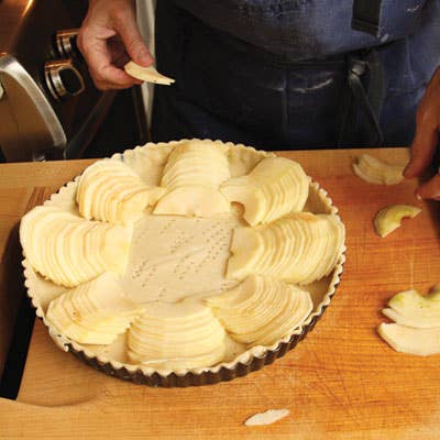 Working with one row at a time, she slides a metal spatula under half the row and transfers it to an unbaked tart shell