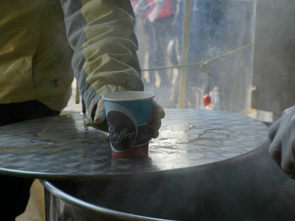 A volunteer serves a cup of tea out of one of the tubs