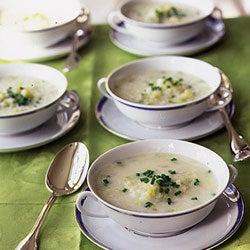 Several white bowls of leek and potato soup.