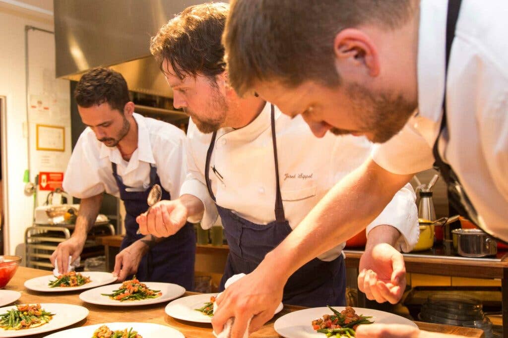 Chef Jared SIppel (center) puts the finishing touches on a salad with his team