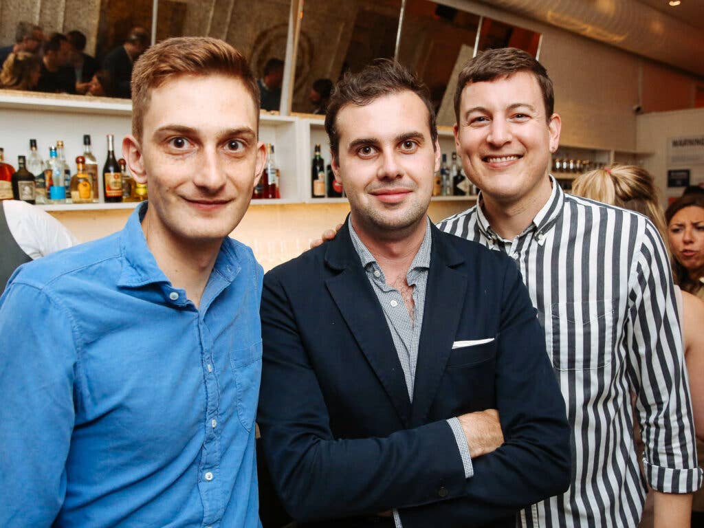 Chris Cohen of SAVEUR, writer Mark Byrne, and Andrew Richdale of SAVEUR pose in front of the bar at Fusco.