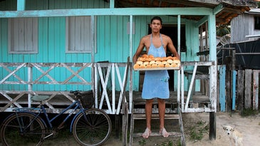 Luciano Lima holds a tray of just-baked rolls at a bakery in the village of Pesqueiro, near Soure.