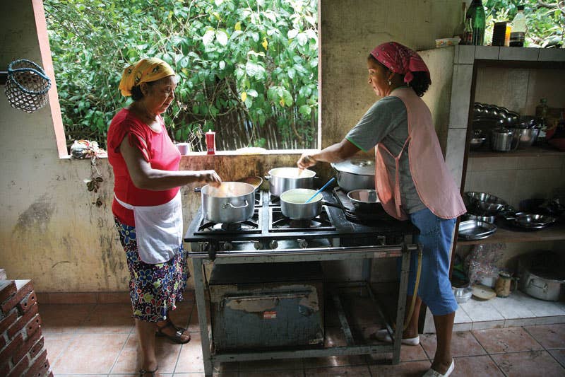 Women prepare a meal in their open-air kitchen.