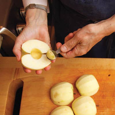 After peeling the apples and cutting them in half lengthwise, she removes the cores with a melon baller.