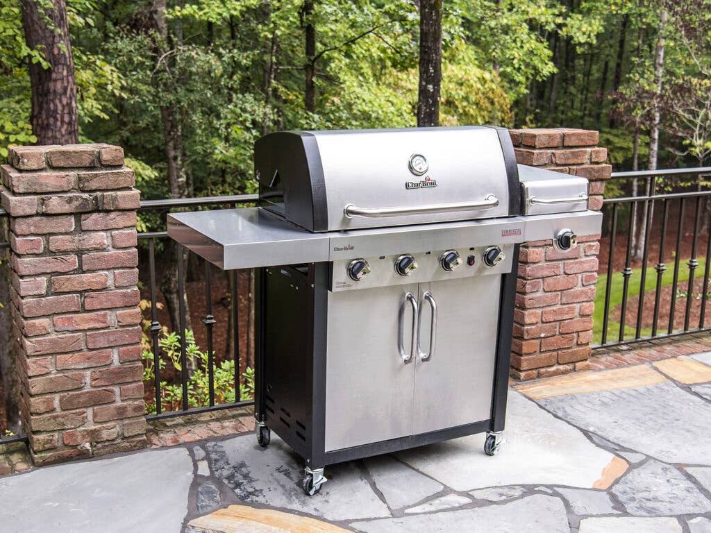 Char-broil grill outside along fence