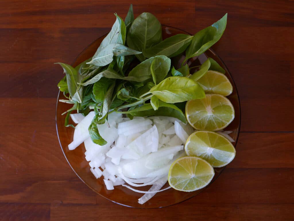 Basil, lime, and onion in a glass dish