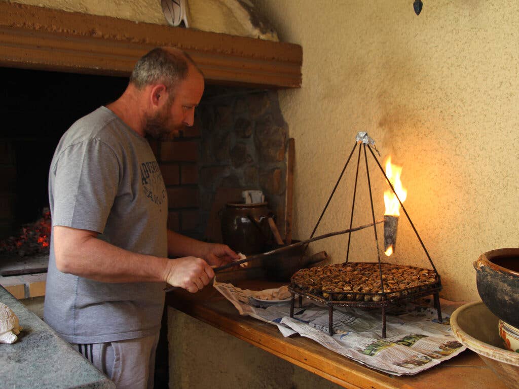 man drizzling flaming lard over snails