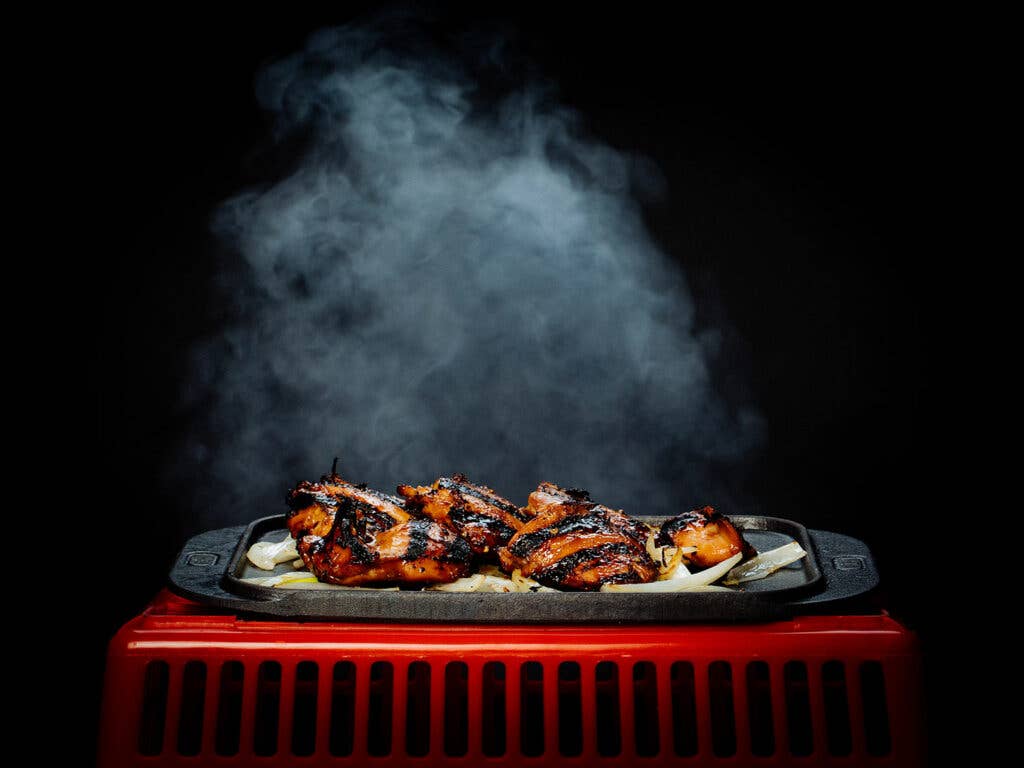 Garlic barbecue chicken steaming on a black background