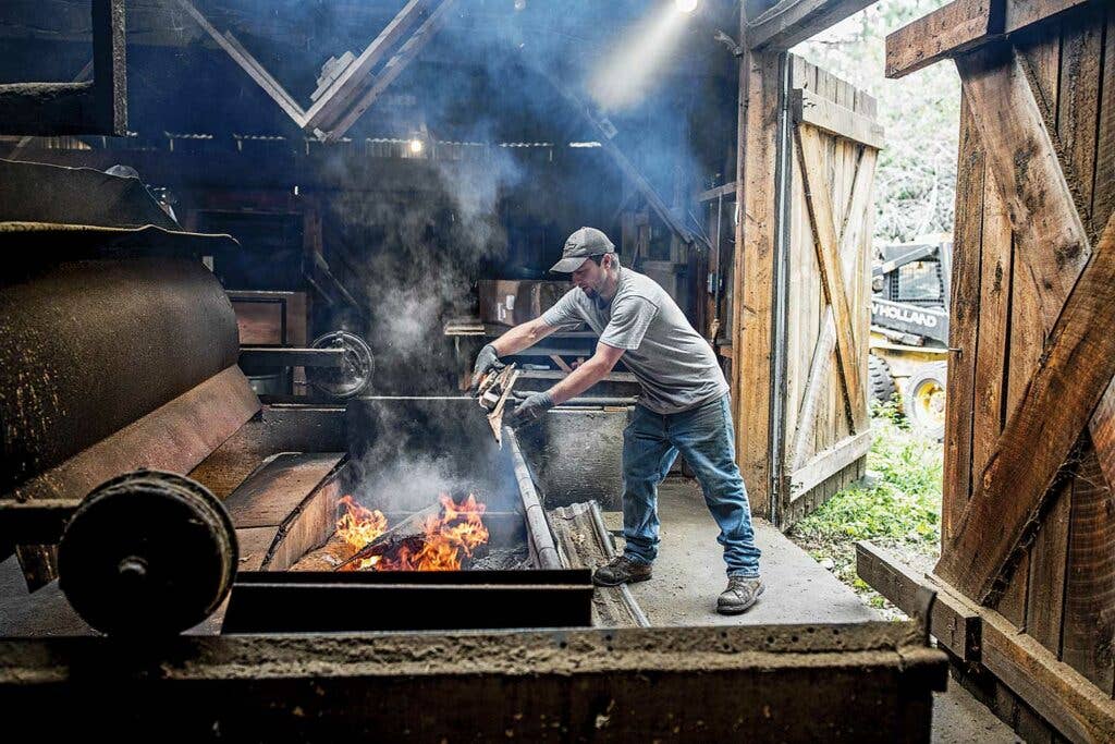 Aaron Dewandeler adds logs to his fire;