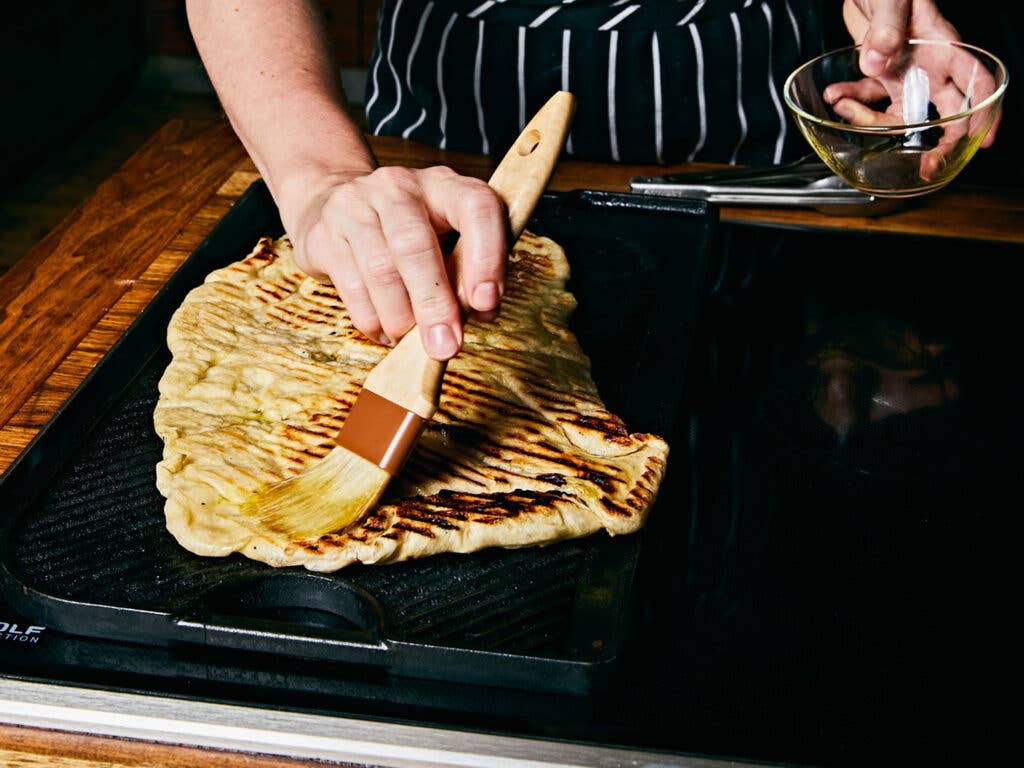 Coating pizza crust with olive oil.