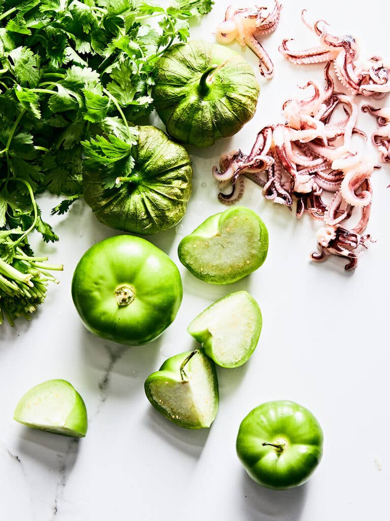 Green tomatillos and purple calamari tentacles on white background.