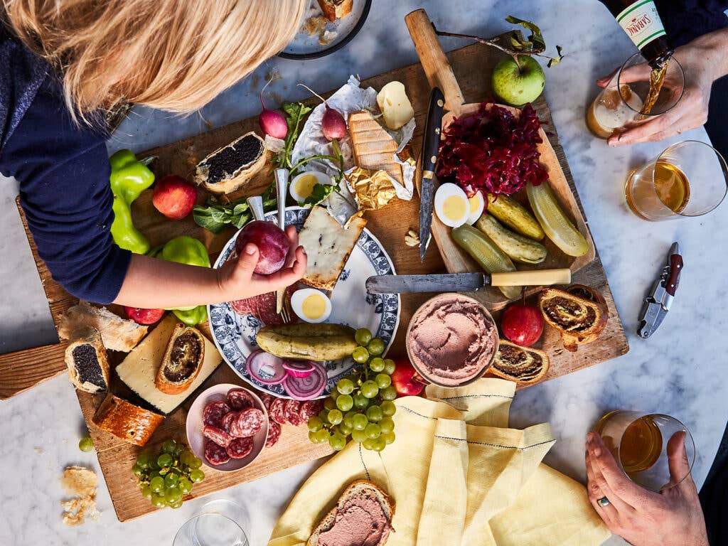 A board of cheeses, meats, pickles, and produce.