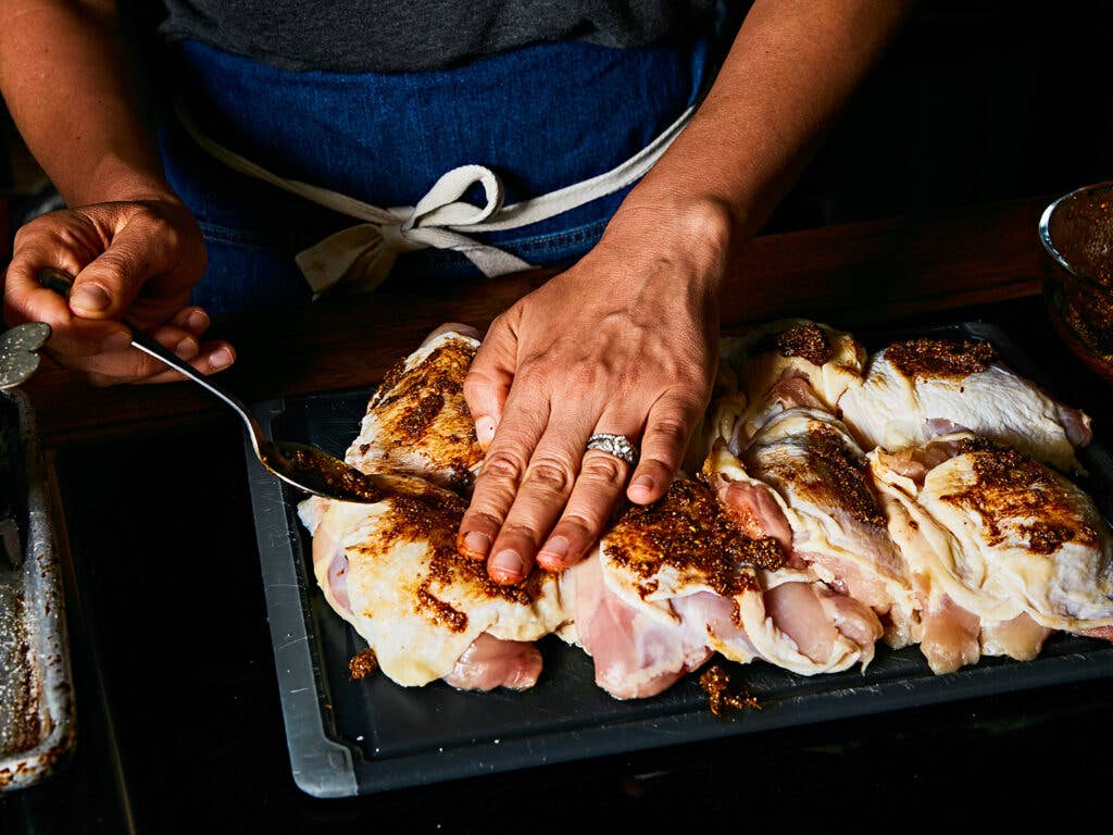 Brushing chicken with olive oil before seasoning with shawarma spice mix.