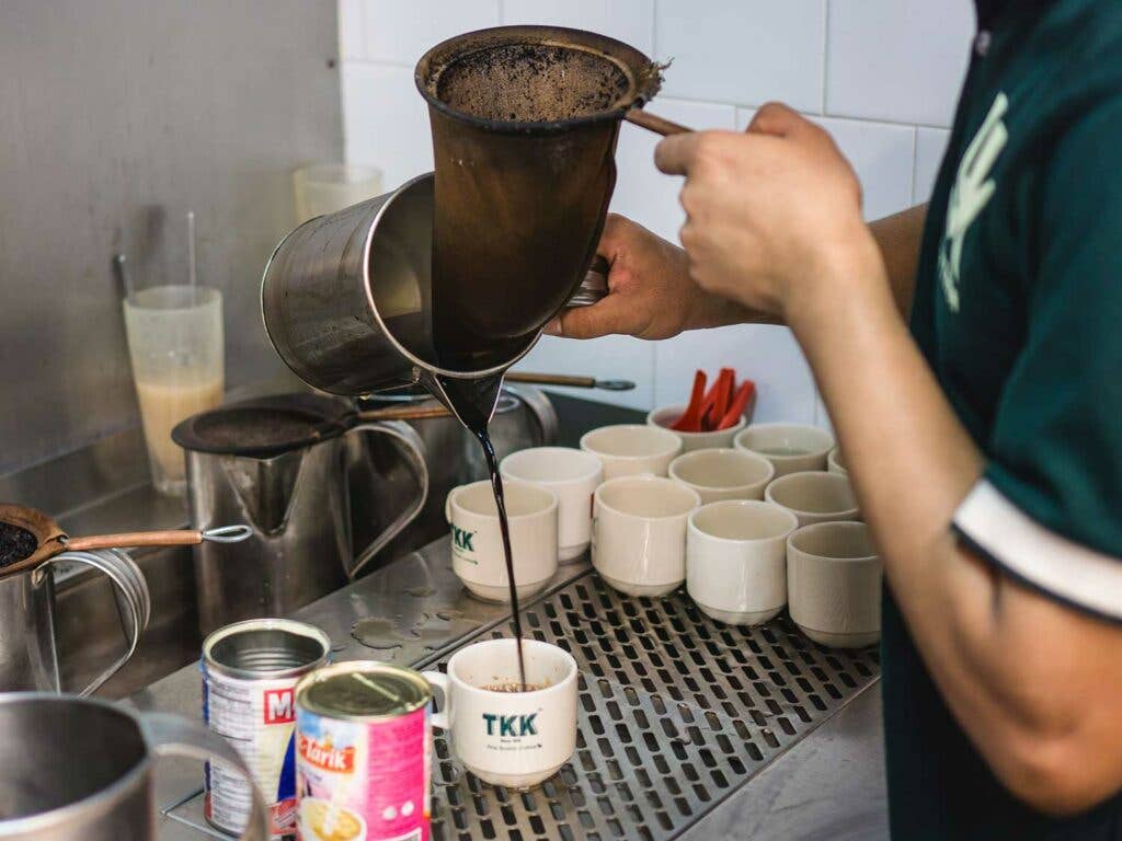 A server pours burnt coffee for breakfast at Yut Kee.