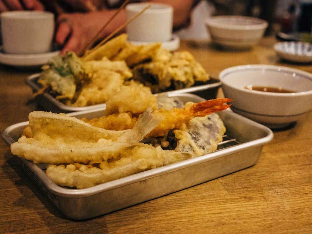 A mixed tempura selection of kisu, prawn, squid, eggplant, okra, lotus root, and maitake mushrooms