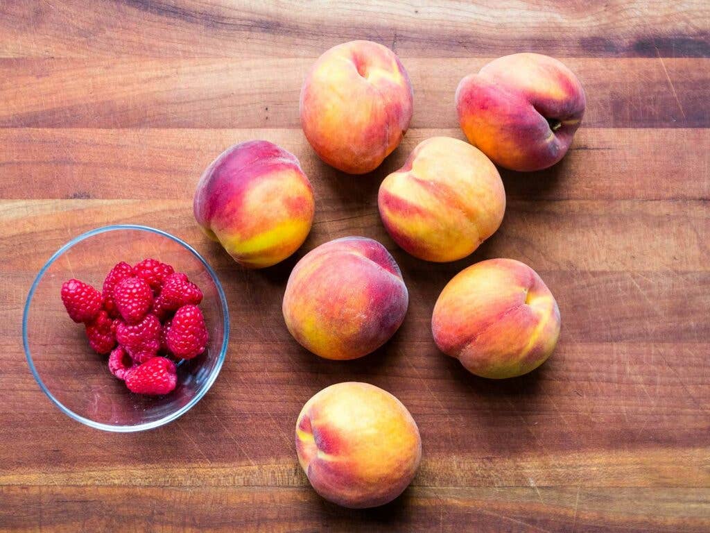 Peaches and raspberries on countertop.