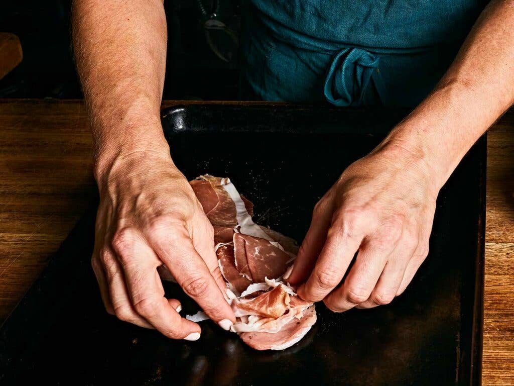 Adding salty prosciutto to the veal.