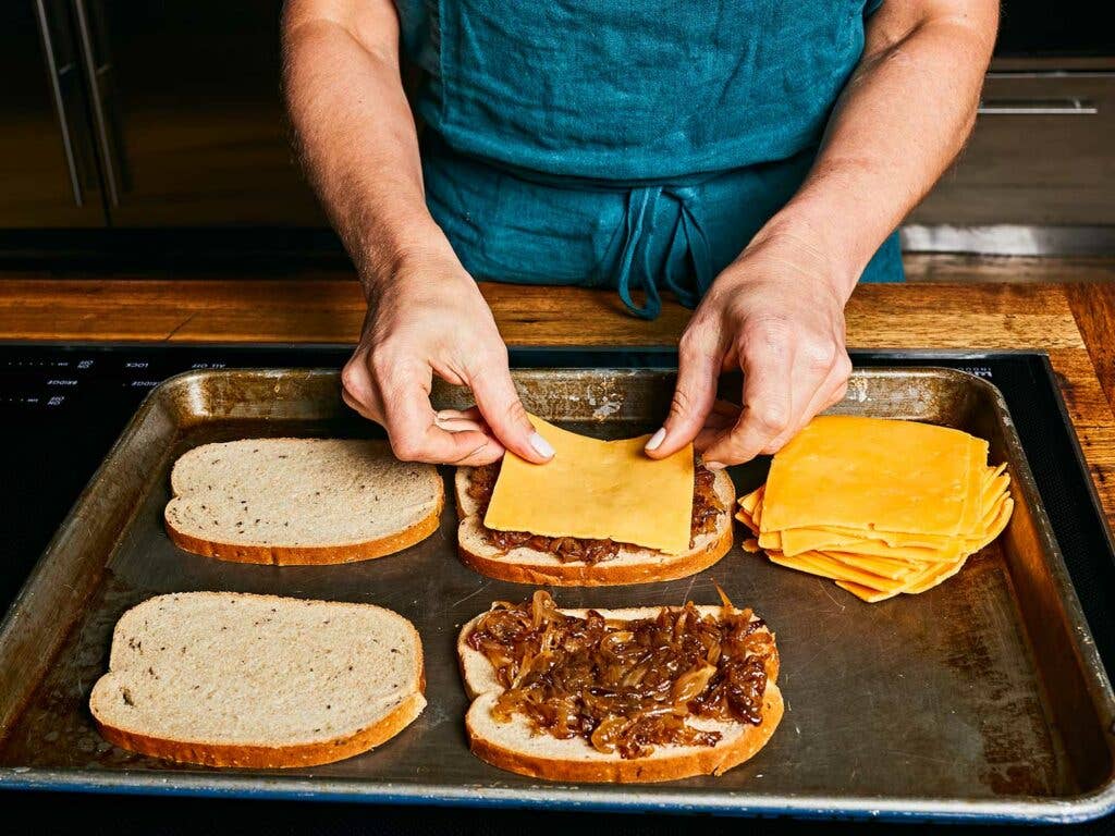 Melting American cheese over grilled onions and bread.