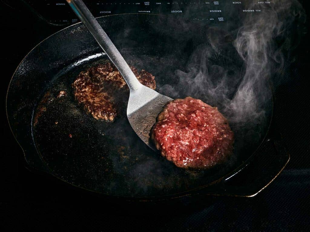 Searing patty on a cast-iron pan.