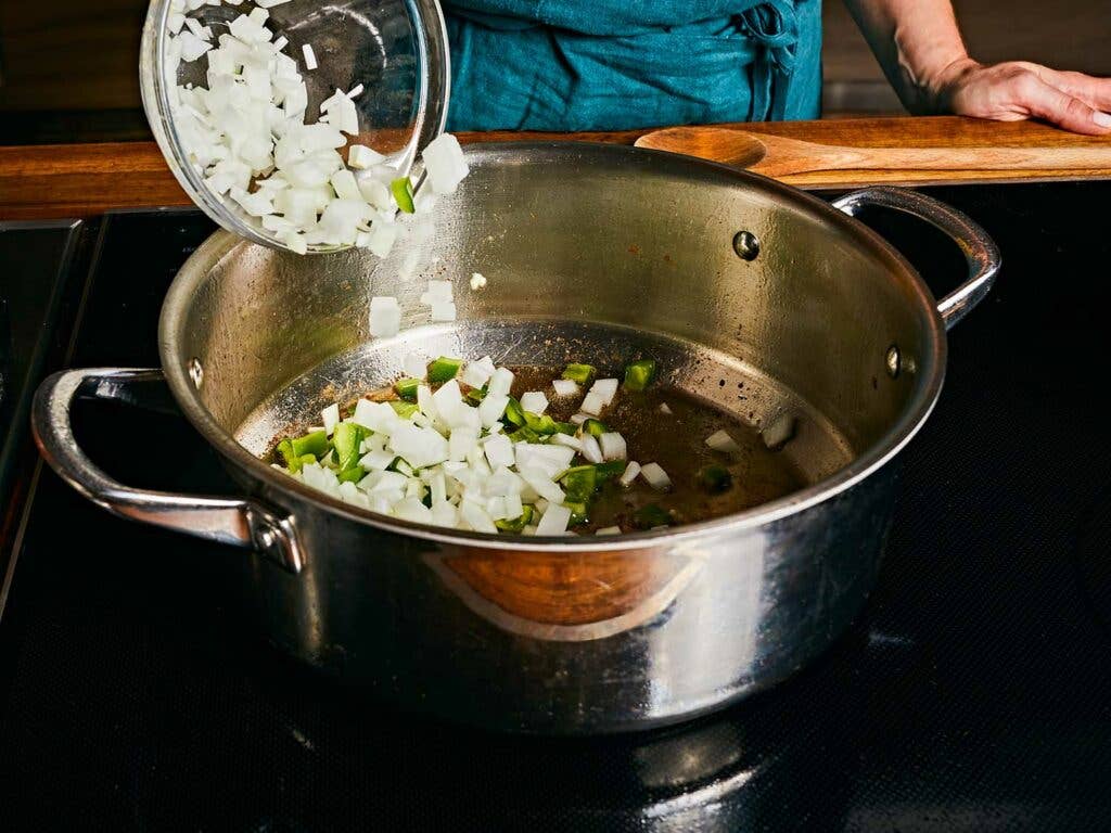 Cooking onion, green bell pepper, garlic, and bay leaves in the chicken fat left in the pot.