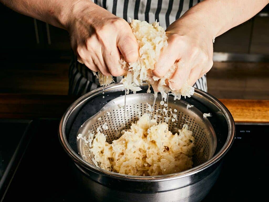 Submerging sauerkraut in cold water, then draining and squeezing out as much moisture as possible.