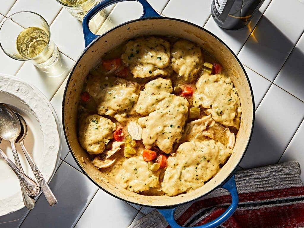 Dumplings cooked on top of chicken in pot.