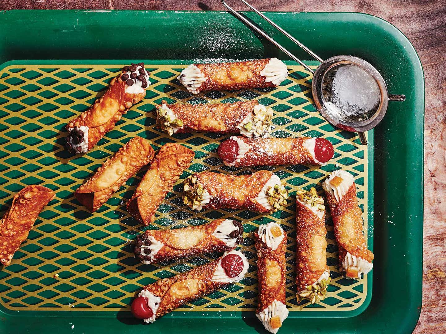 Cannolis with chocolate chips, raw pistachios, candied orange peels, and maraschino cherries.