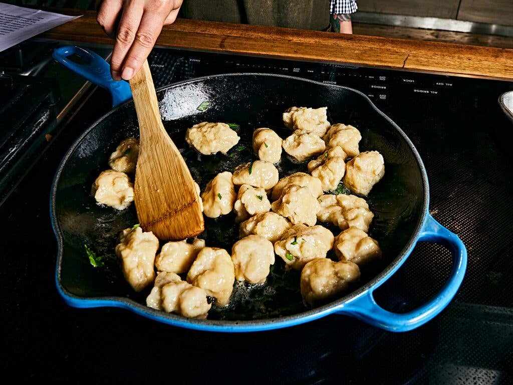 Stirring dumpling with butter and parsley in the skillet.