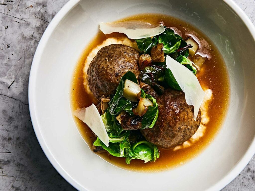 Wagyu beef meatballs over polenta with sunchokes, greens, and Parmesan cheese.