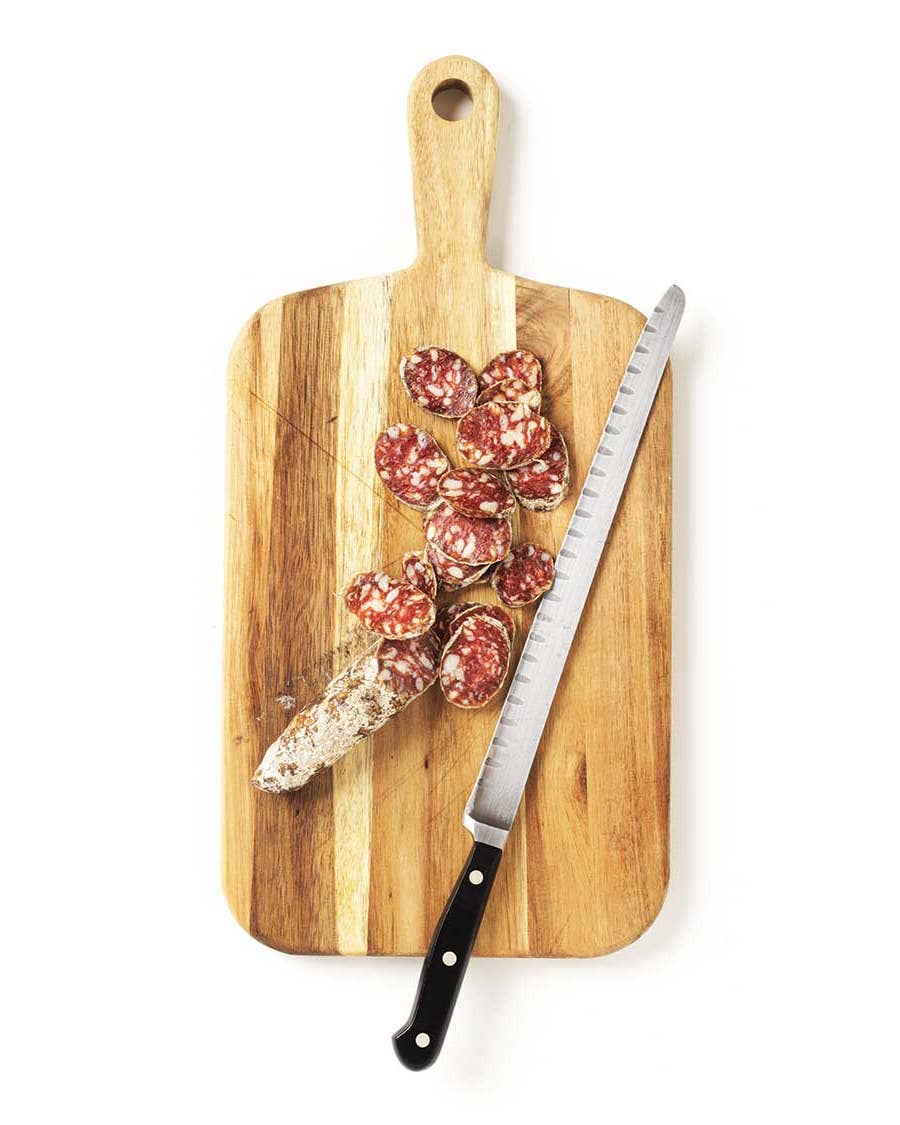 Salami cut on cutting board with knife.
