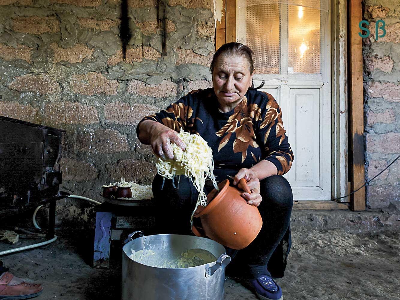 Woman cooking pasta in metal pot.