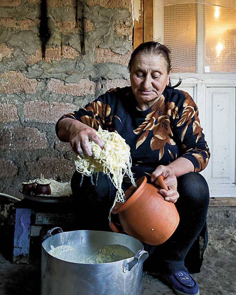 Woman cooking pasta in metal pot.
