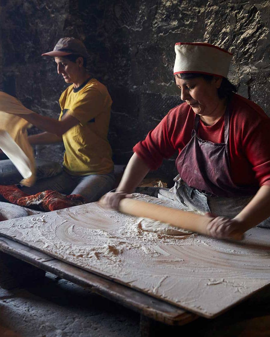 Women roll out lavash dough.