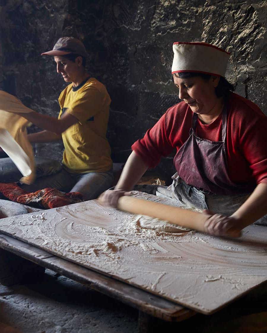 Demystifying the Breads of Armenia Women roll out lavash dough.