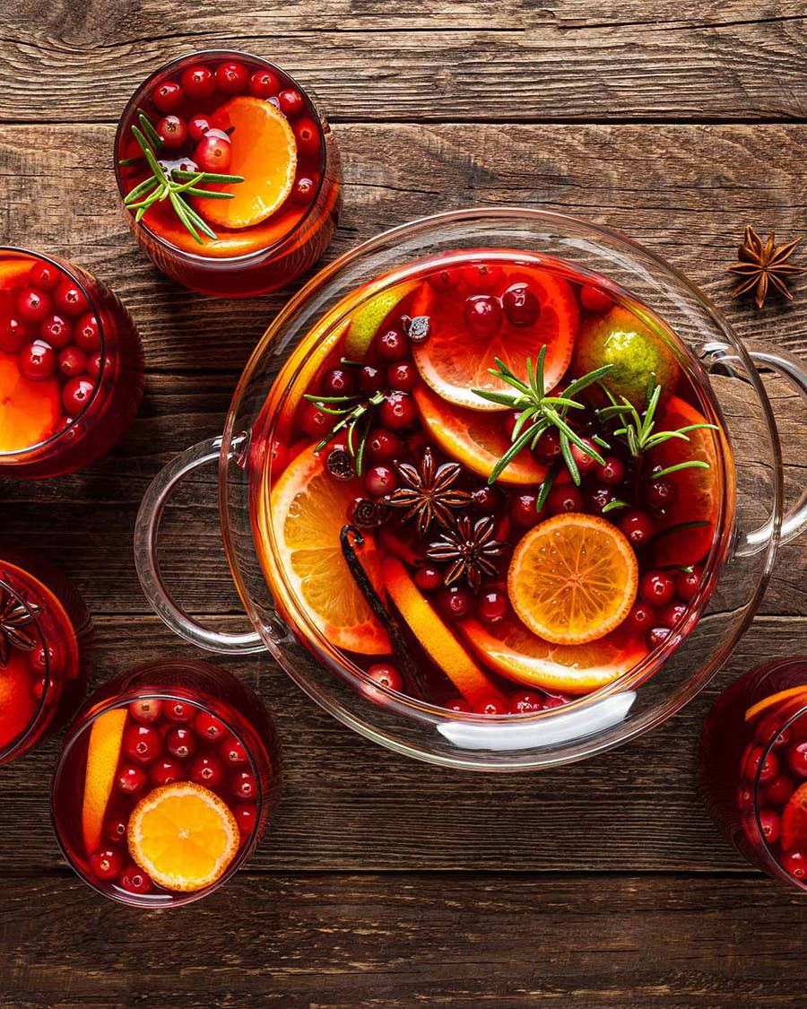 Punch bowl full of orang slices, cranberries, and punch.