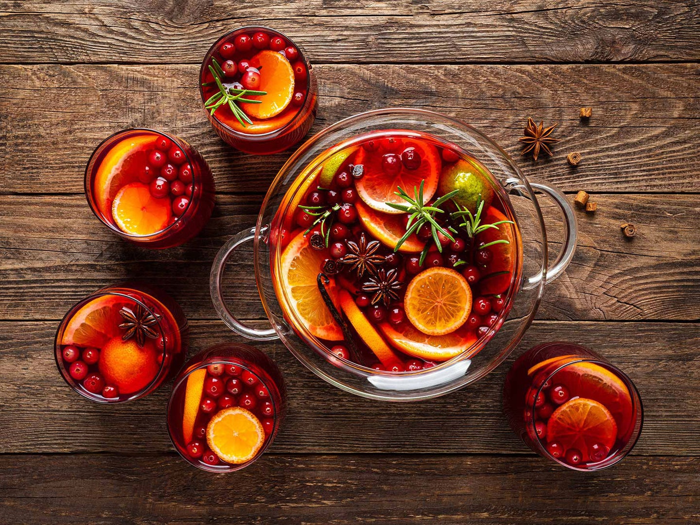 Punch bowl full of orang slices, cranberries, and punch.