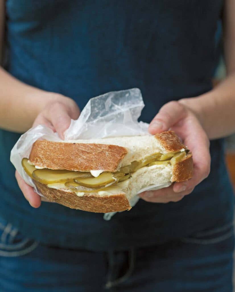 Person holding a bread-and-butter pickle sandwich
