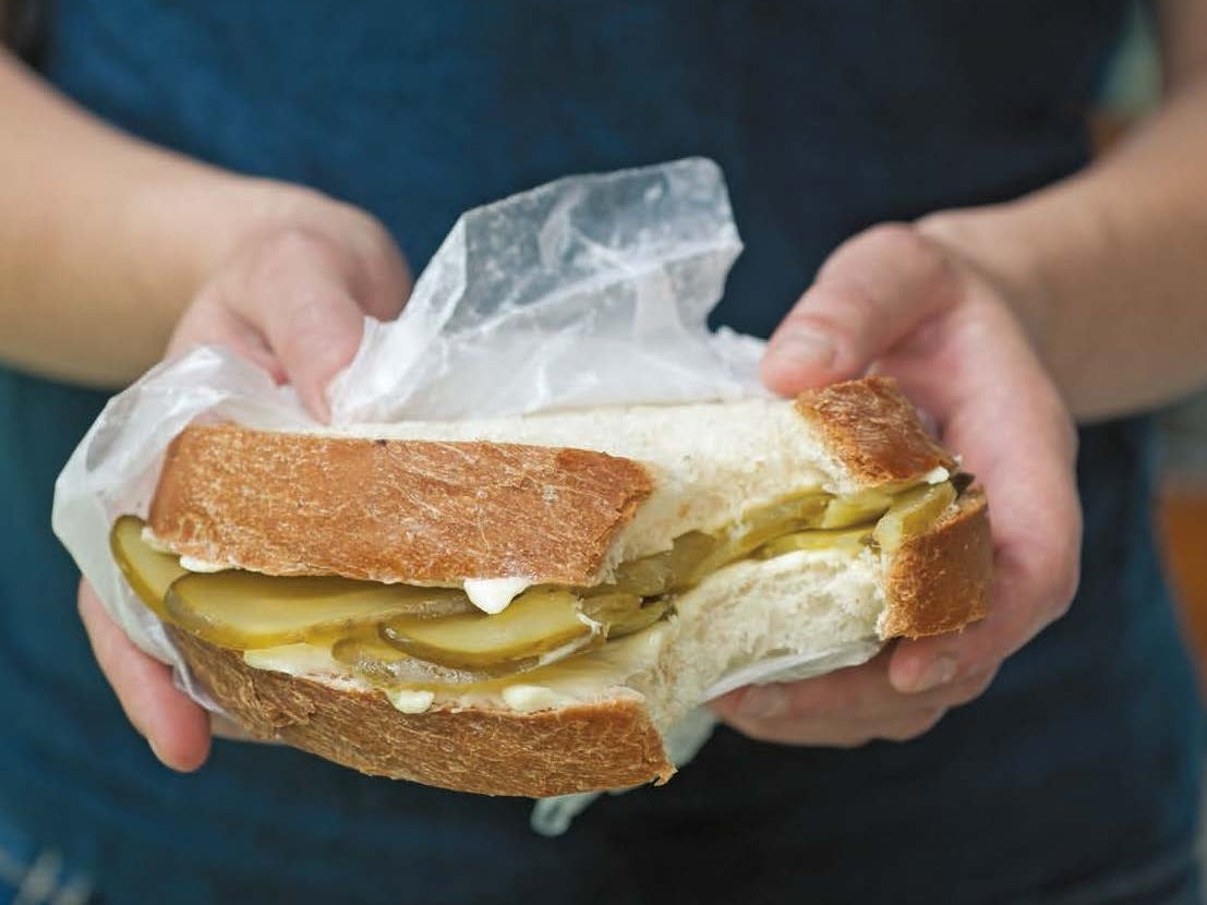 Person holding a bread-and-butter pickle sandwich