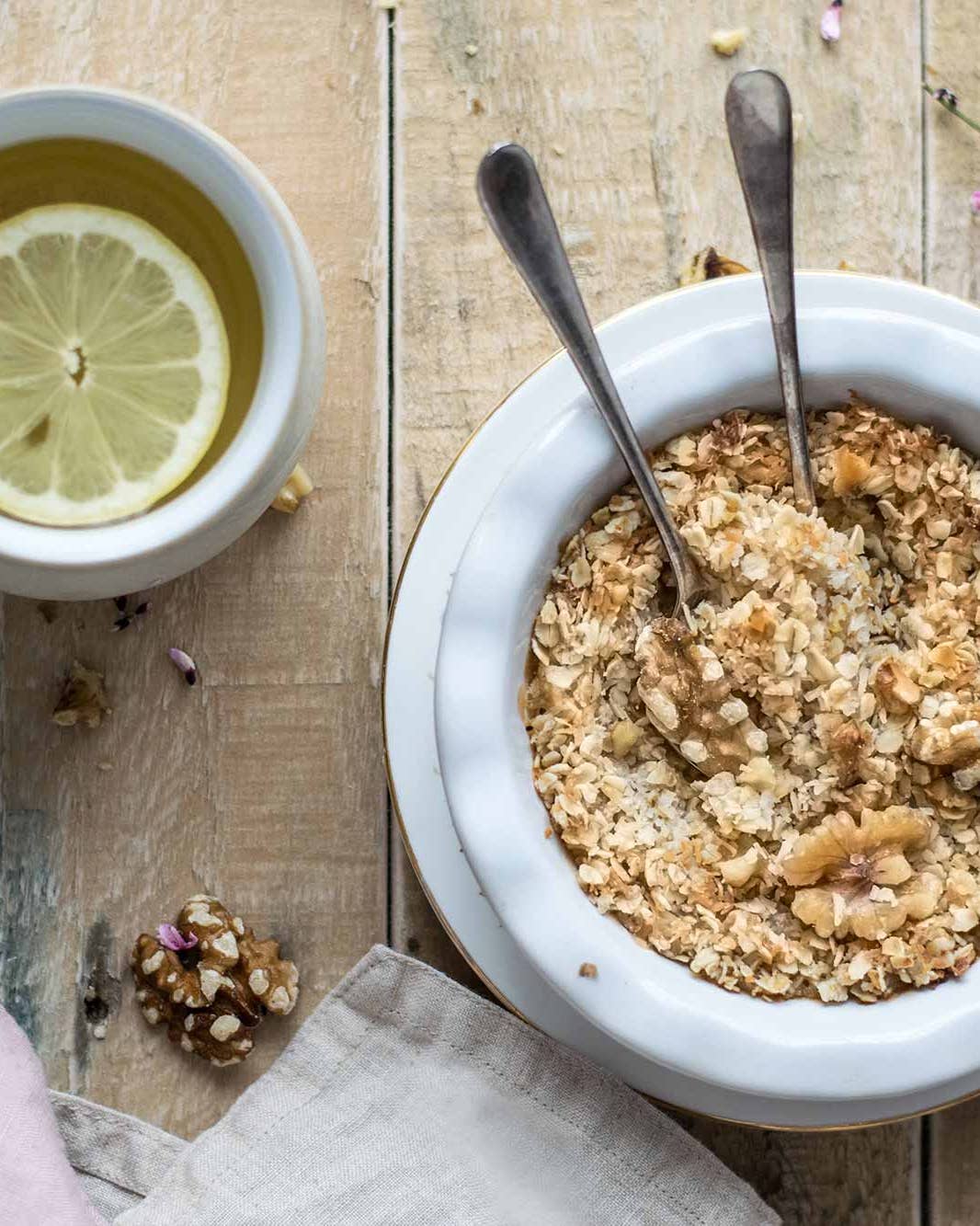 Bowl of oatmeal and cup of tea with lemon.