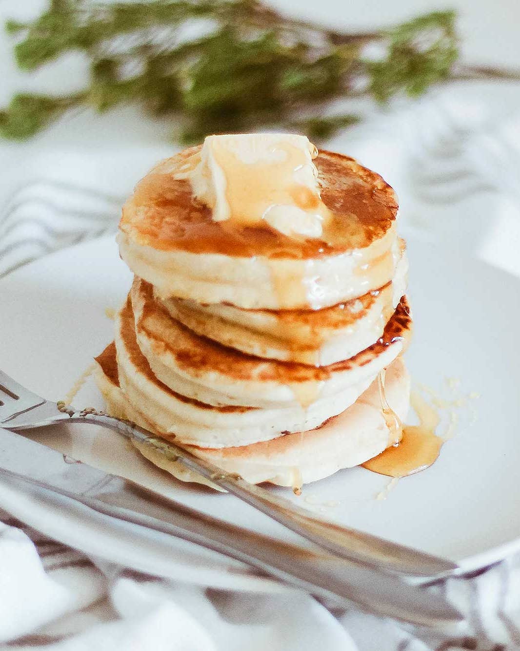 Stack of pancakes with chunk of butter and syrup dripping