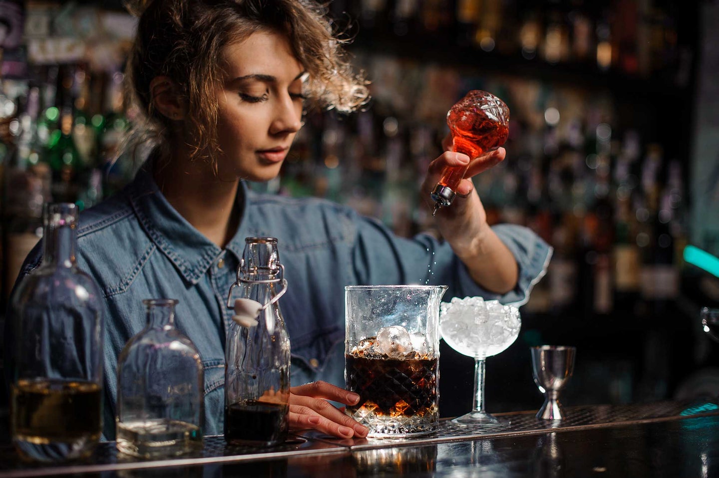 Bartending dashing bitters into a cocktail