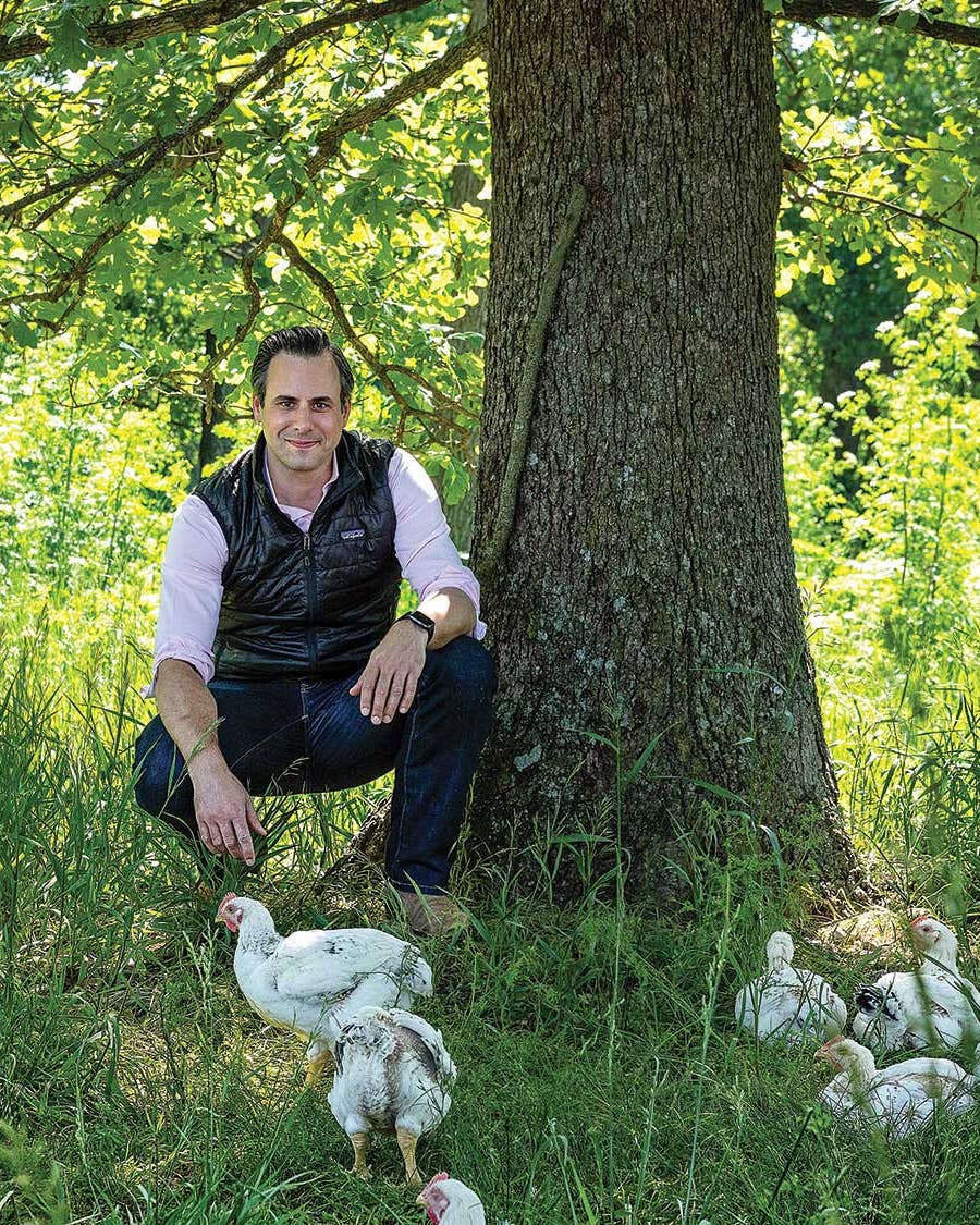 Matt Wadiak, co-founder and CEO of Cooks Venture, at the operation’s 800-acre farm in Decatur, Arkansas sitting under tree with chickens.