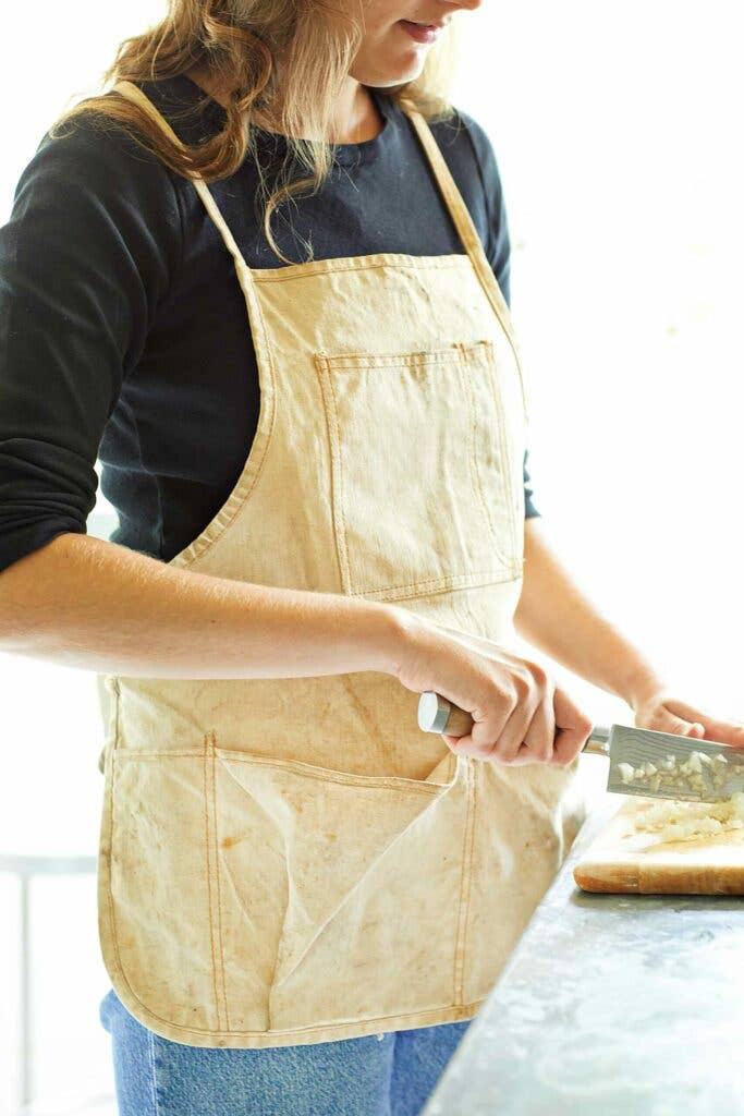 Woman chopping vegetables in a canvas apron