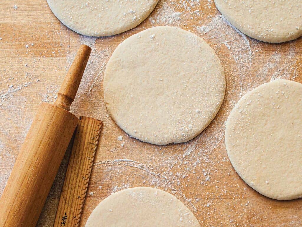 Balls of dough flattening into 6-inch discs.