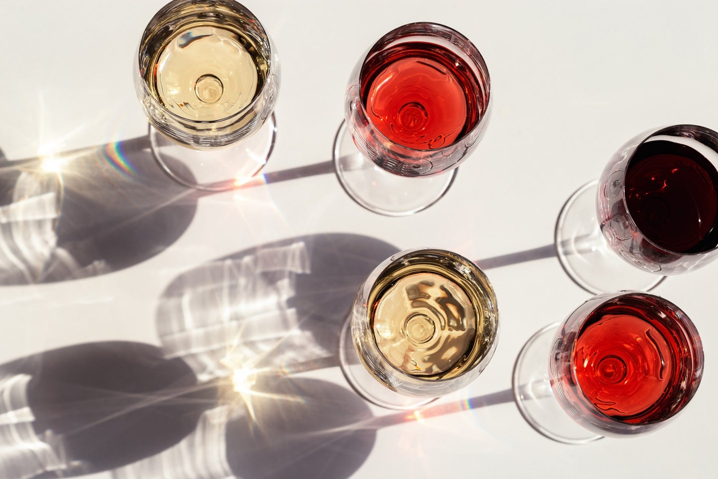 Red, rose and white wine top view in sunlight. Assorted wine in glass. Dark shadows.